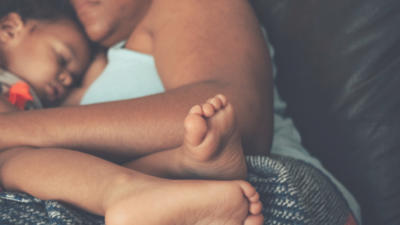 A woman and child napping on a couch.